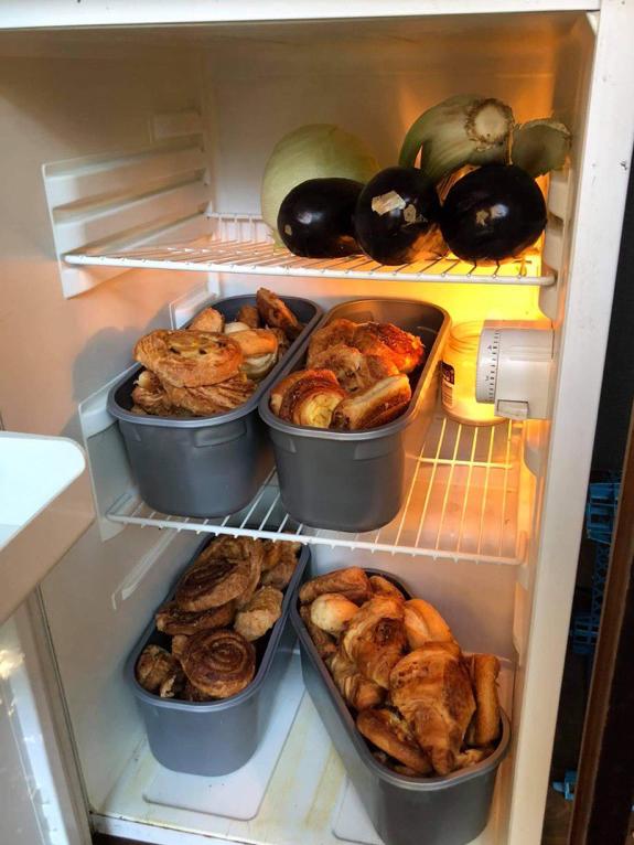 Inside of a community fridge showing man saved pastry and some vegetables