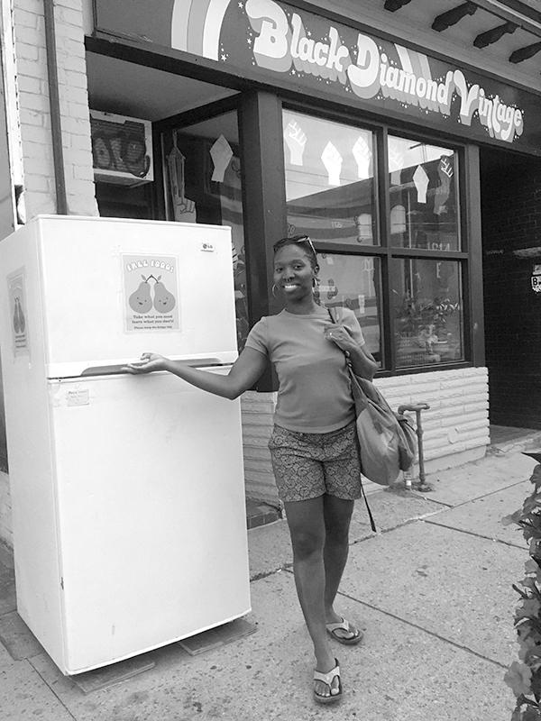 A woman is standing next to a Parkdale community fridge in Toronto, which was shut down by Toronto city.